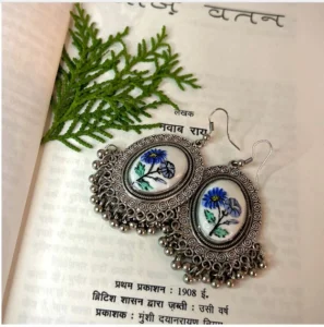 A pair of elegant, royal-style earrings with a deep violet, banafsha (sweet violet) flower design.