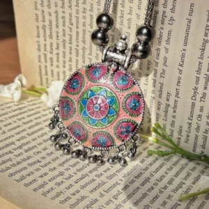 An oxidized brass necklace with a hand-painted and engraved design, coated with a glossy resin finish.