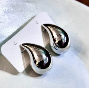 A pair of simple, small stud earrings with a shiny silver finish.