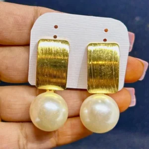 A pair of drop earrings with a small gold or silver post and a smooth, round pearl dangling from a delicate chain.