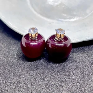 A pair of whimsical drop earrings with a small stem and two red cherry charms.