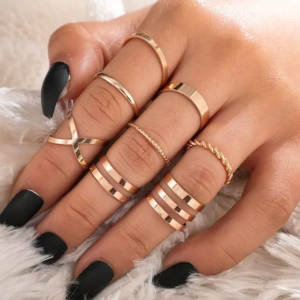 A collection of eight assorted golden rings, including minimalist bands, rings with small stones, and geometric designs.