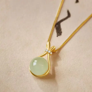 A minimalist pendant with a small, smooth, round charm in a deep olive green color.