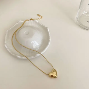 : A simple, gold-plated pendant in the shape of a smooth heart, hanging from a thin chain.