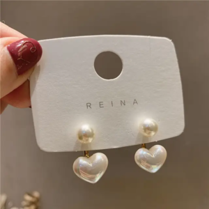 A pair of delicate drop earrings with a small heart charm and a dangling pearl.