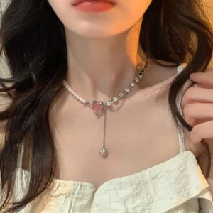 A necklace with a pink heart-shaped pendant, decorated with shimmering cubic zirconia and a small pearl.