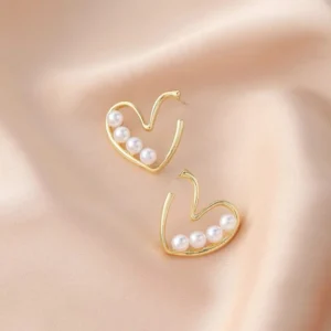 A pair of small stud earrings with a heart shape made from tiny, white pearls.