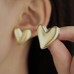 Gold heart-shaped earrings on a woman's ear close-up view
