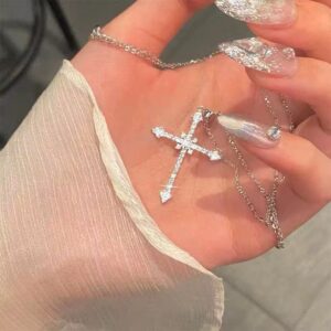 Elegant hand holding a sparkling silver cross necklace